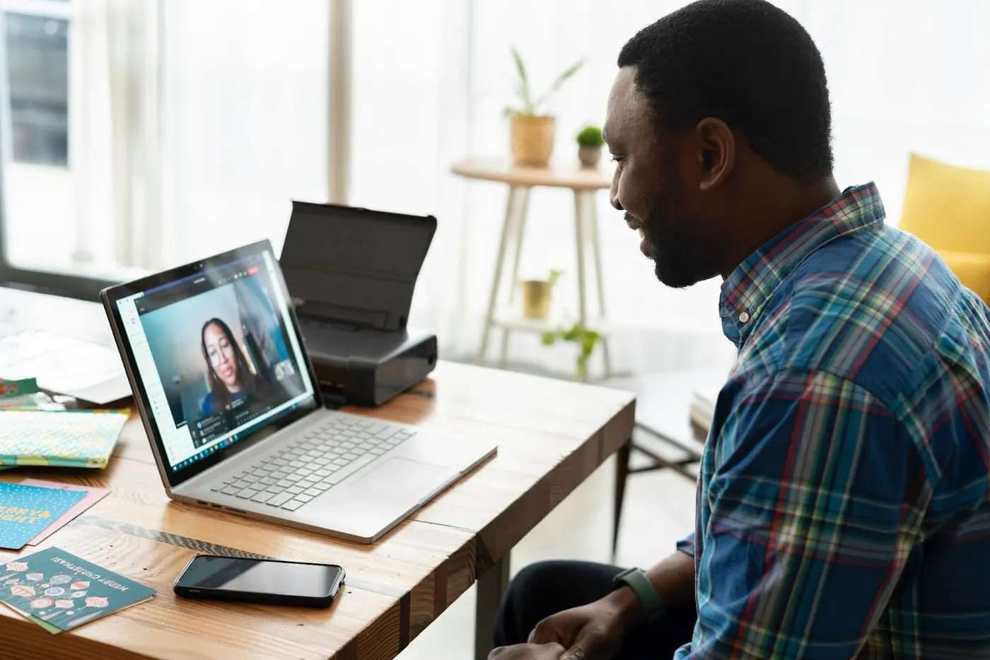 A photo of a professional siting at a desk, looking at a laptop screen, and engaging in a virtual event.
