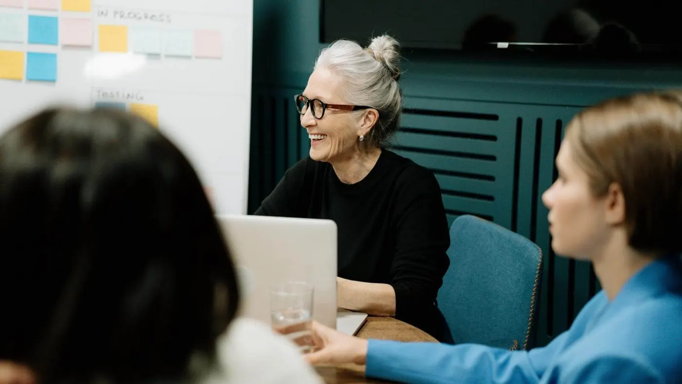 woman-in-black-sweater-and-eyeglasses-sitting-on-chair-beside-woman-in-blue-shirt