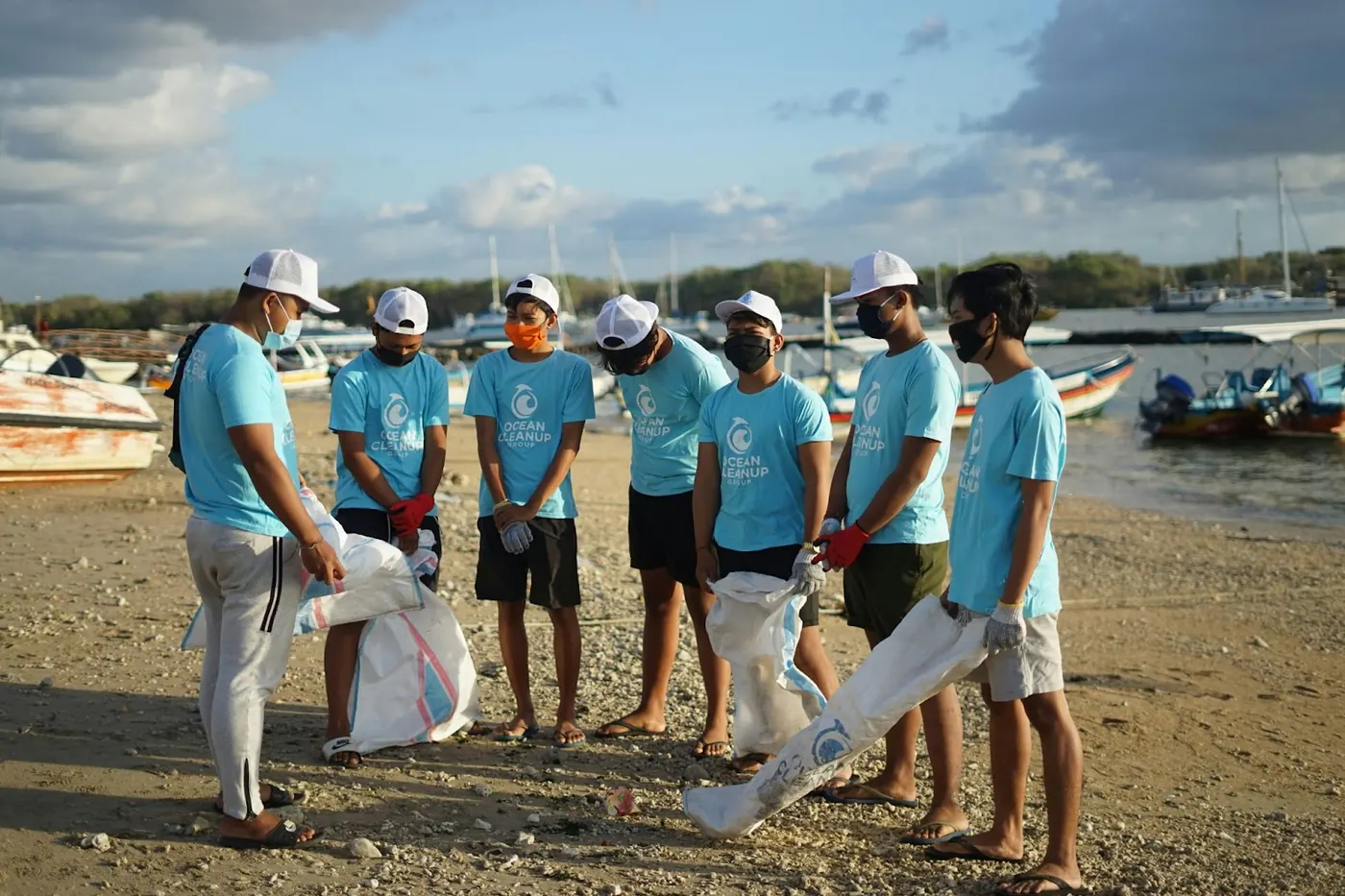 A photo of a group of people doing a beach clean up wearing matching shirts.